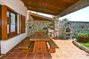 patio z drewnianym stołem i kamienną ścianą w obiekcie Holiday Home Orihi w mieście Barban