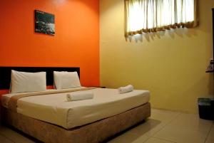 um quarto com 2 camas e uma parede laranja em Wau Hotel & Cafe em Jerantut