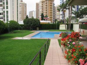 a swimming pool in a park with flowers and buildings at Apartamentos Torre Ipanema in Benidorm