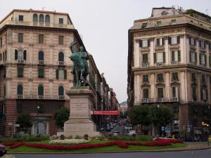 a statue in the middle of a city with buildings at Actor Hotel in Genoa