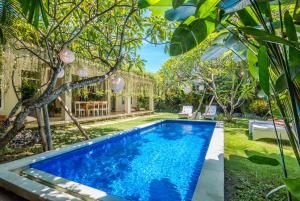 a pool in the backyard of a house with trees at Villa Lodek Deluxe in Seminyak