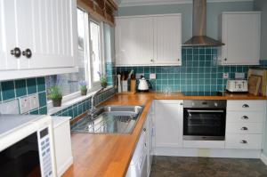 a kitchen with white cabinets and a sink at Craignethan in Kames