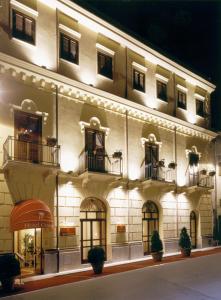 un grande edificio bianco con finestre e balconi di notte di Hotel Centrale Spa & Relax ad Alcamo