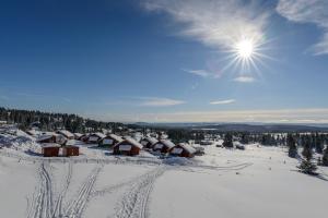 un pueblo cubierto de nieve con el sol en el cielo en Lillehammer Fjellstue og Hytteutleie, en Nordseter