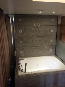 bañera en una habitación con espejo en Jungle City Motel en Chiayi