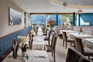 un restaurante con mesas y sillas blancas y ventanas en Hotel Paradies en Tirolo