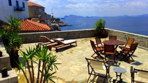 een patio met stoelen en tafels en uitzicht op het water bij Villa Castello in Hydra