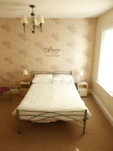 1 dormitorio con 1 cama y una pared con flores en The Northwood, en Colwyn Bay