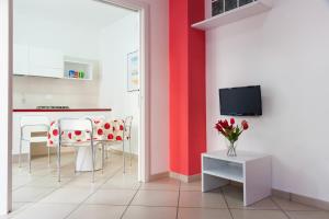a kitchen with a red wall and a table and chairs at Settessenze Residence & Rooms in Agropoli