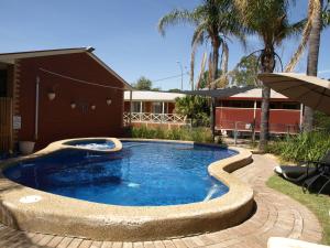 een zwembad in een tuin naast een gebouw bij Old Coach Motor Inn Echuca in Echuca
