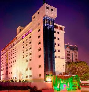 Un grand bâtiment blanc avec des lumières allumées la nuit dans l'établissement JP Chennai Hotel, à Chennai