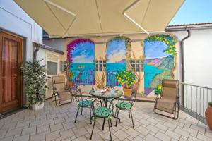 a patio with a table and chairs in front of a mural at Casa Generosa in Agerola +12 photos