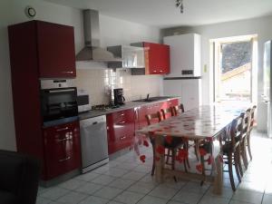 uma cozinha com armários vermelhos e uma mesa com cadeiras em Gite de victor em Gigny-sur-Suran