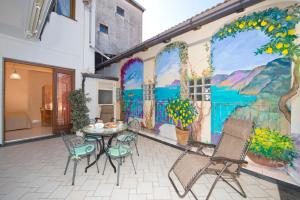 un patio con tavolo e sedie di fronte a un murale di Casa Generosa ad Agerola