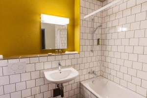 a bathroom with a sink and a tub and a mirror at Hotel ZwiBack in Dübendorf