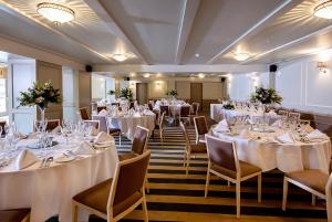 斯蒂夫尼奇Hotel Cromwell Stevenage的配有桌椅和白色桌布的房间