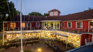 a large red building with a deck with tables at Pärnu Jahtklubi Külalistemaja in Pärnu