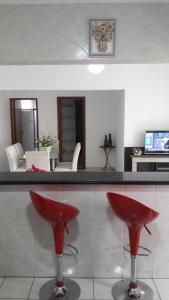 un bar con taburetes rojos en la sala de estar en Apartamento Luxo Praia Grande en Praia Grande