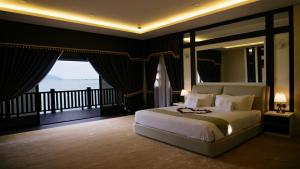 ein Schlafzimmer mit einem großen Bett und einem Balkon in der Unterkunft Casuarina Pangkor in Pulau Pangkor