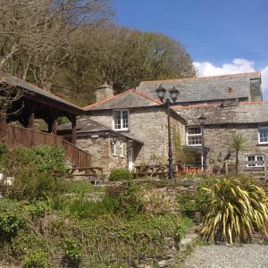 an old stone house with a staircase in front of it at The Mill House in Tintagel