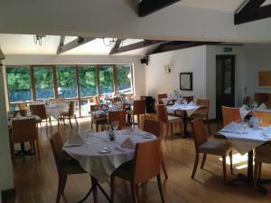 a dining room with tables and chairs and windows at The Mill House in Tintagel