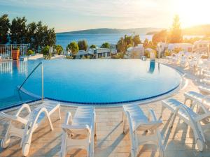 uma grande piscina com cadeiras brancas ao redor em Easyatent Luxe Safari tent Krk em Krk