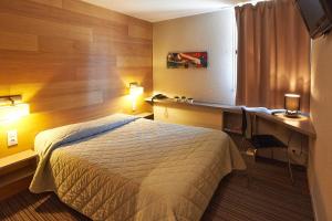 Habitación de hotel con cama, escritorio y escritorio. en Cit'Hotel Les Alizés, en Limoges