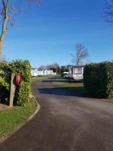 a driveway with a campsite in the background and a house at Holly Cottage in Burgh le Marsh