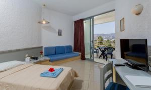 a hotel room with a bed and a tv and a balcony at Dessole Dolphin Bay - All Inclusive in Amoudara Herakliou