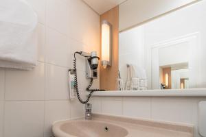 ein Bad mit einem Waschbecken und einem Spiegel in der Unterkunft ibis Koblenz City in Koblenz