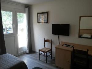 a hotel room with a bed and a desk with a television at Le Provence in Manosque +24 photos