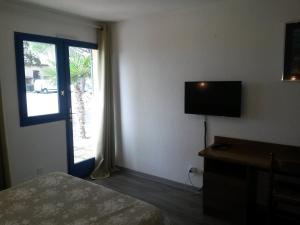 a hotel room with a bed and a television and a window at Le Provence in Manosque