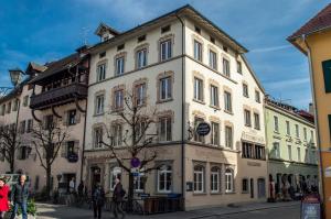 ein großes weißes Gebäude mit Leuten, die davor laufen in der Unterkunft K-Hotel (Grüner Baum) in Überlingen