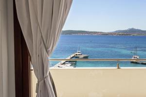 een raam met uitzicht op de oceaan en boten bij Hotel Miralonga in La Maddalena