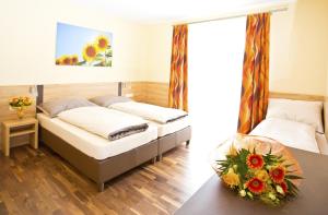 um quarto com duas camas e uma mesa com flores em Pension Einsiedl em Ottenschlag