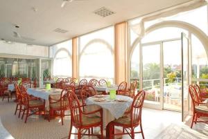 a dining room with tables and chairs and windows at Hotel Riviera 3 Stelle con piscina estiva gratuita e garage a pagamento in Spotorno