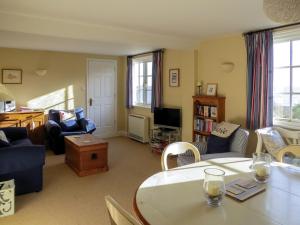 uma sala de estar com um sofá, uma mesa e cadeiras em Ogilvie Lodge Apartment em Thorpeness