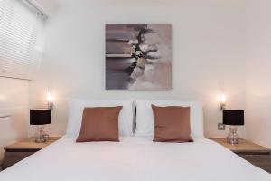 a bedroom with a white bed with two lamps at Apartment near Harrods in London