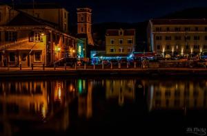 eine Stadt in der Nacht mit einer Reflexion im Wasser in der Unterkunft Apartment Marija in Tisno