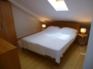 a bedroom with a large white bed with two lamps at Apartment Marija in Tisno