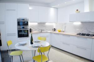 a white kitchen with yellow chairs and a white table at Casa Maria in Zoagli