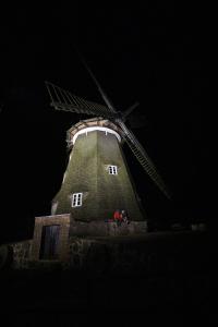 two people standing in front of a windmill at night at Ferienhaus am Mühlenberg in Benz