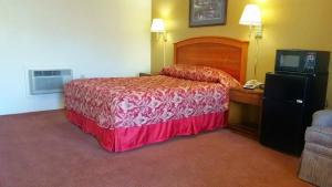 a hotel room with a bed and a television at Travelers Inn in New Martinsville +2 photos