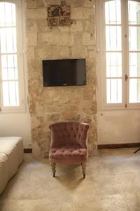 a room with a chair and a television on a stone wall at Cité des Papes in Avignon