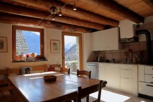 una cucina con tavolo in legno e una cucina con vista di Casa Dosc a Verdabbio