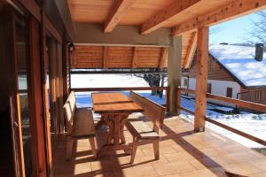 a wooden table and bench on a porch with snow at Holiday Home Edi in Delnice