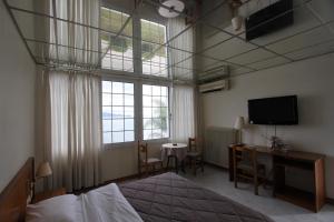 a bedroom with a bed and a desk and a television at Miloi Rooms and Apartments in Míloi