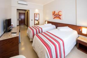 una camera d'albergo con due letti e una televisione di Hotel Carlton Plaza a Poços de Caldas