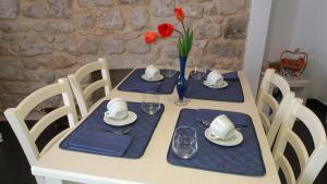 a white table with blue napkins and red flowers on it at Reusia Holiday Home in Ragusa