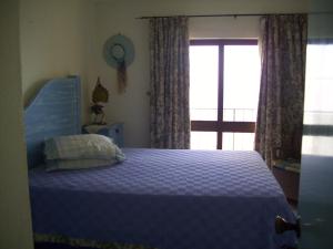 a bedroom with a blue bed and a window at Algarve terraço da Bela Vista Edf Cruzeiro in Portimão